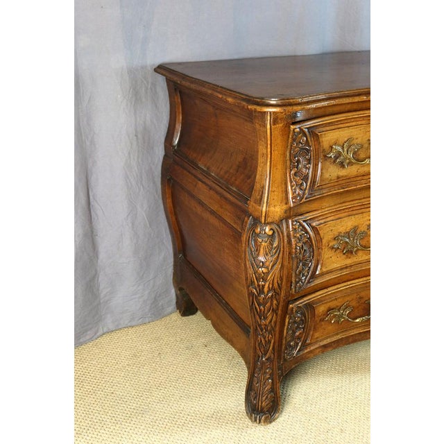 A Lyon-style walnut commode with a curved front, opening with three drawers, including a secret drawer in the top drawer....