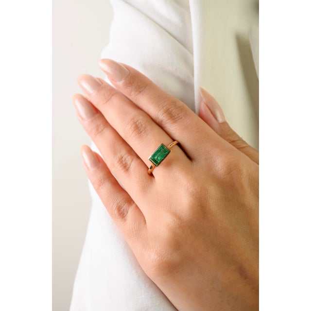 This elegant solitaire ring features 1 natural emerald cut emerald totaling 0.89 carats, set in 14k yellow gold. The...