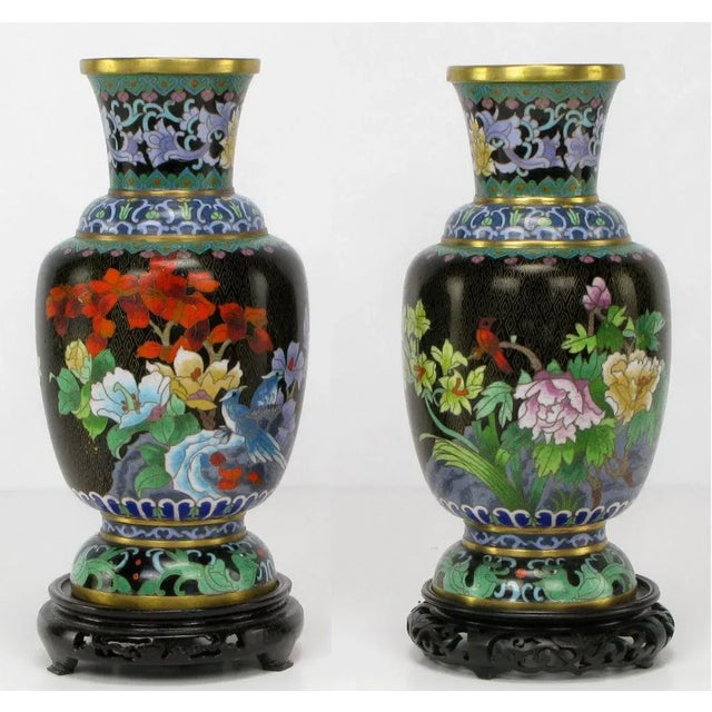 Pair of Chinese floral-decorated and mirror-image black cloisonne vases. Colorful flora and fauna depicted in green, red,...