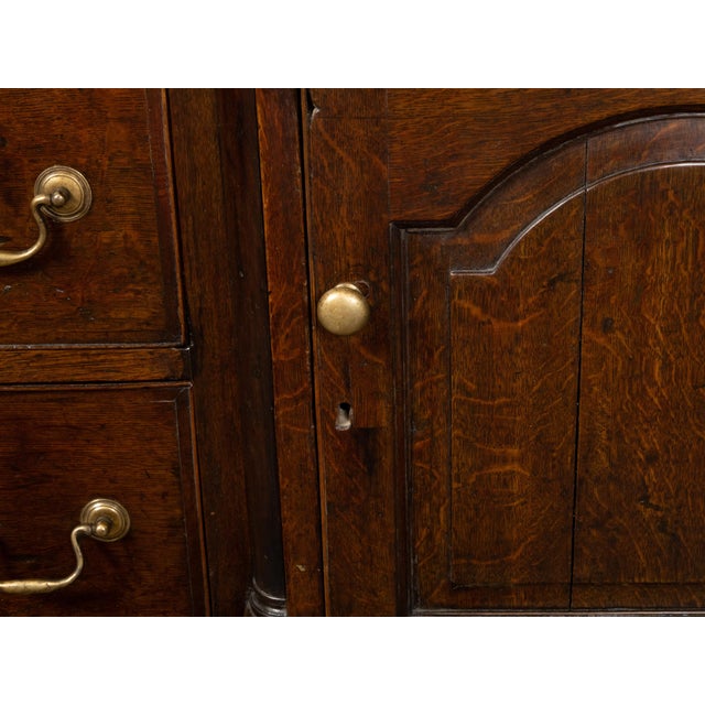 An English Georgian period oak dresser base from the early 19th century, with five drawers, two doors, brass hardware and...