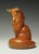 This bronze sculpture features a gracefully curled fox, its sleek form and smooth surface reflecting a warm, reddish hue....