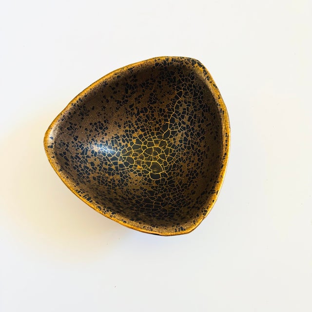A hand made mid century pottery bowl. Triangular shape. Features a black and gold crackle glaze the the interior with a...