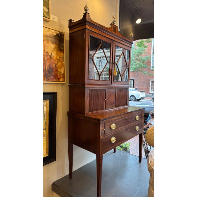 This is a vintage American tambour secretary. It is Sheraton style. It has a shelf with doors that open and lock. It also...