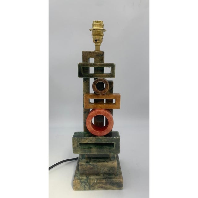 The alabaster lamp features a slender and elegant shape, with a tapered base reminiscent of a column. The body and base...
