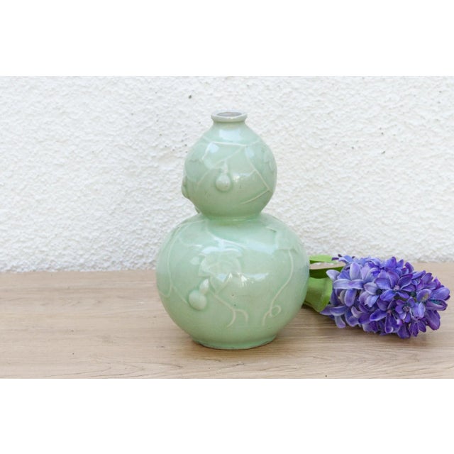 This unique vase is a masterpiece of symbolism and form, crafted to hold good wishes. This antique celadon vase, likely...