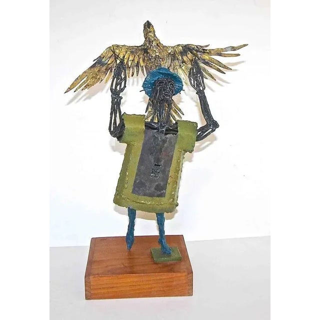 Original metal sculpture of man holding eagle mounted on wood base by renown Texas artist and sculptor, Bob Fowler...
