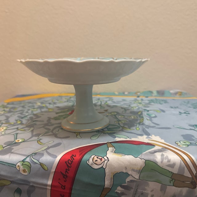 A charming vintage porcelain compote or pedestal dish executed in a striking turquoise blue hue. The center features an...