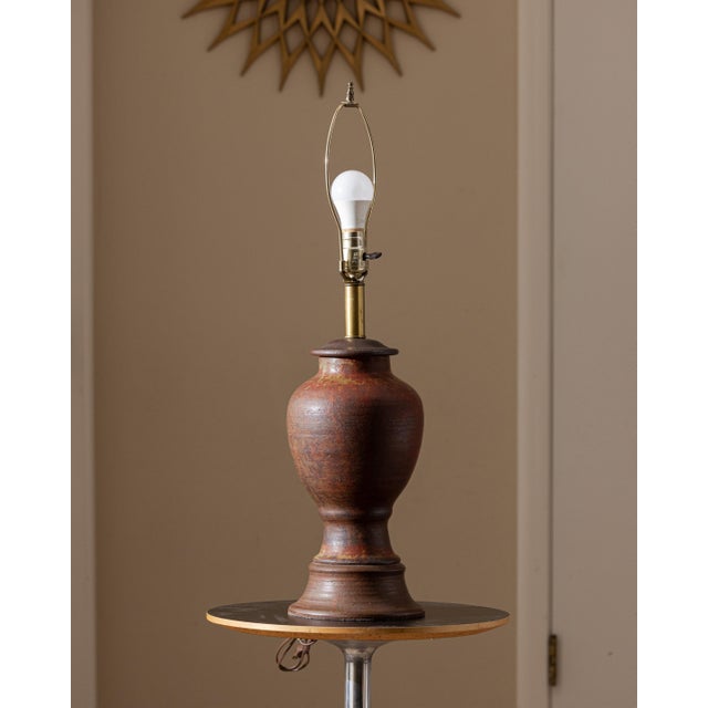 A signed and dated studio pottery table lamp by Petzold, created in 1973. Hand-thrown ceramic construction with a richly...