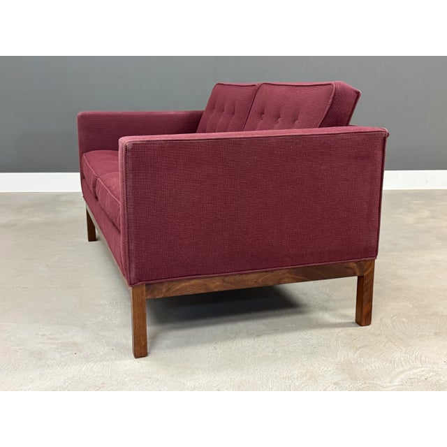 A maroon purple tweed loveseat sofa with a walnut base in the style of Florence Knoll. Made in USA. Circa 1960’s. Minor...