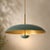 sculptural pendant light featuring a broad, gently curved dome shade in a rich green finish with a warm brass-toned...