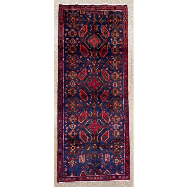 Hand-knotted runner from the Hamadan region of western Iran, featuring a series of geometric medallions aligned along the...