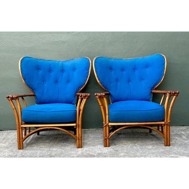 This pair of vintage Heywood Wakefield lounge chairs sets a sculptural, wing-shaped back against a warm bent rattan frame....
