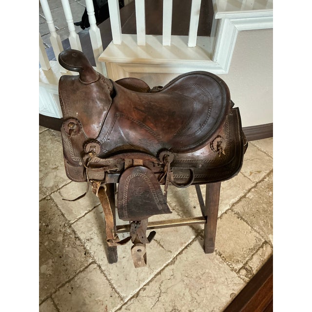 beautifully hand‑tooled vintage Western saddle, richly detailed with floral carving, decorative edging, and classic...