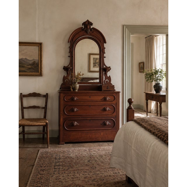 This antique wooden dresser features an impressive arched mirror, sculpted drawer pulls, three generous drawers, and a...