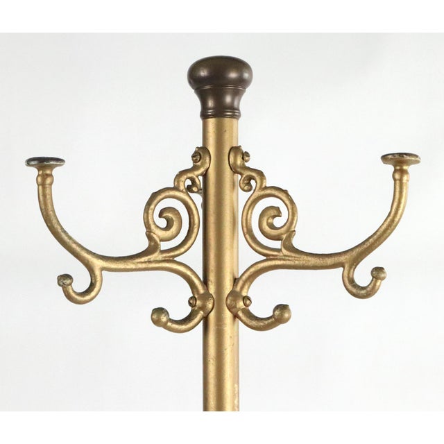 Victorian styled steel coat tree rack with a bright gold painted finish and elaborate scrolling details around the base...