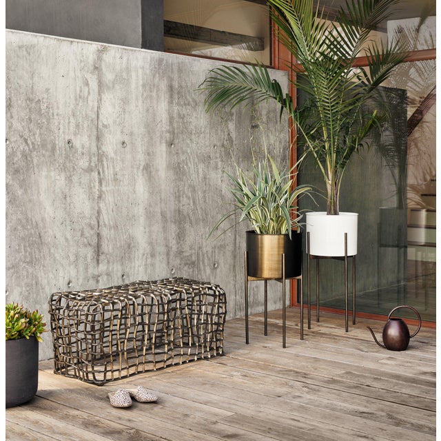 Slim legs of dark brass-finished iron support an inset planter of rounded weathered brass iron. Plastic plant liner...