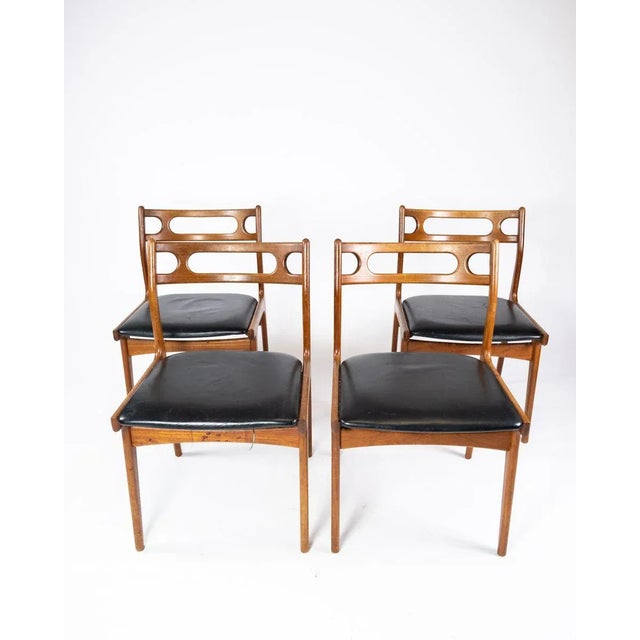 A set of four dining room chairs of teak and upholstered with black leather of Danish design from the 1960s. The chairs...