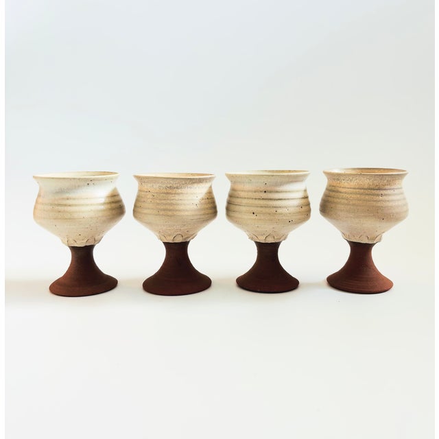 A set of 4 vintage studio pottery goblets. Each with a speckled off white bowl and terra cotta stems. Each measures...