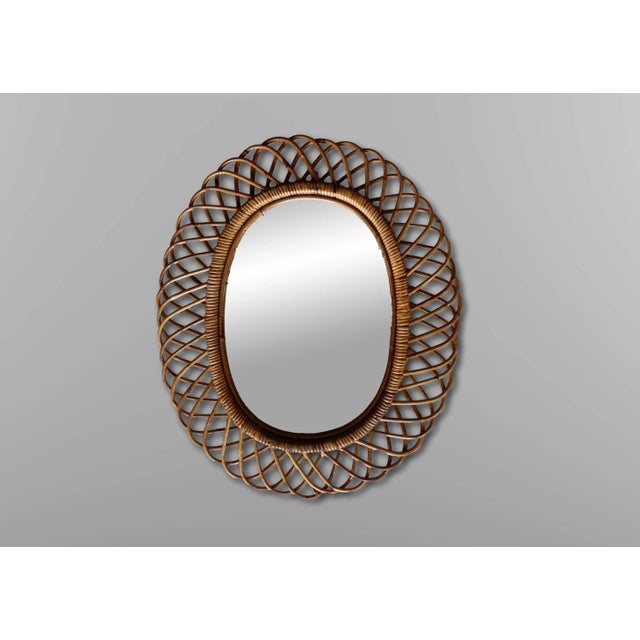 Italian rattan wall mirror (circa 1960s). The mirror has a complex rattan weave in a series of horseshoe projections on...