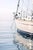 Minimalist coastal artwork featuring a sailboat resting on calm water with soft reflections and clean lines. The...
