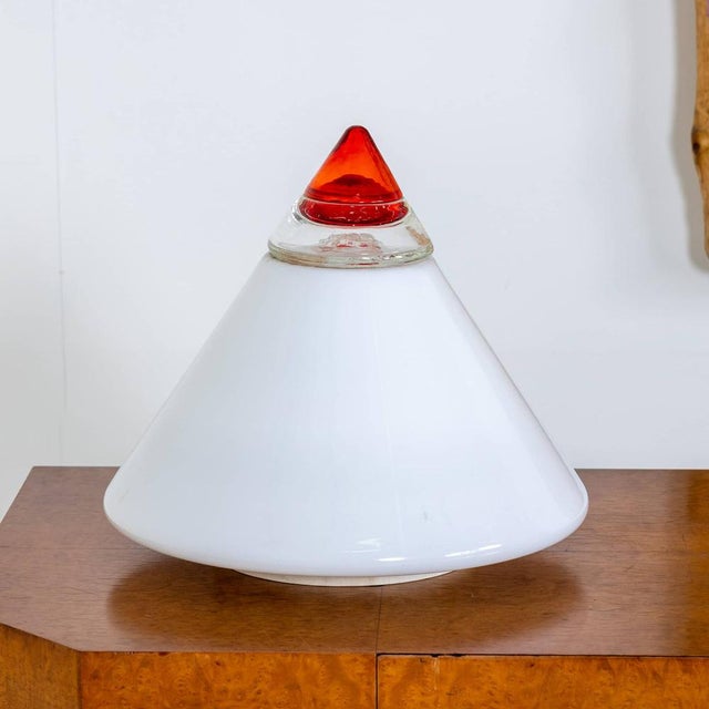 Conical table lamp in white glass tapering to a red tip. Label on the side "Leucos Hand Crafted - Made in Italy". This...