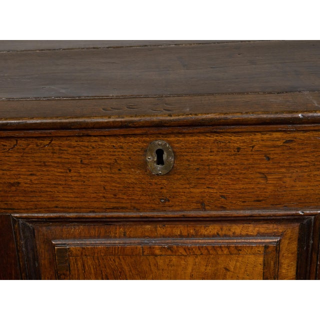 An English Georgian period oak mule chest from the early 19th century, with lift top, three drawers and brass hardware....