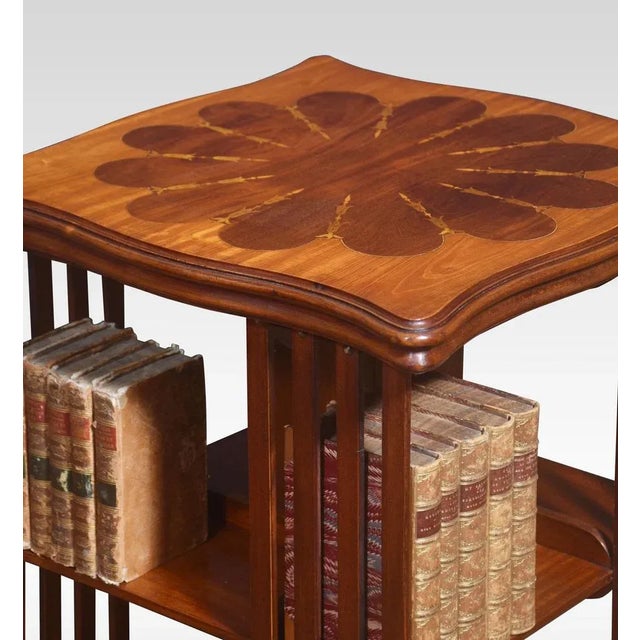 Mahogany revolving bookcase the inlaid shaped top above an arrangement of shelves and slat supports raised up on a...