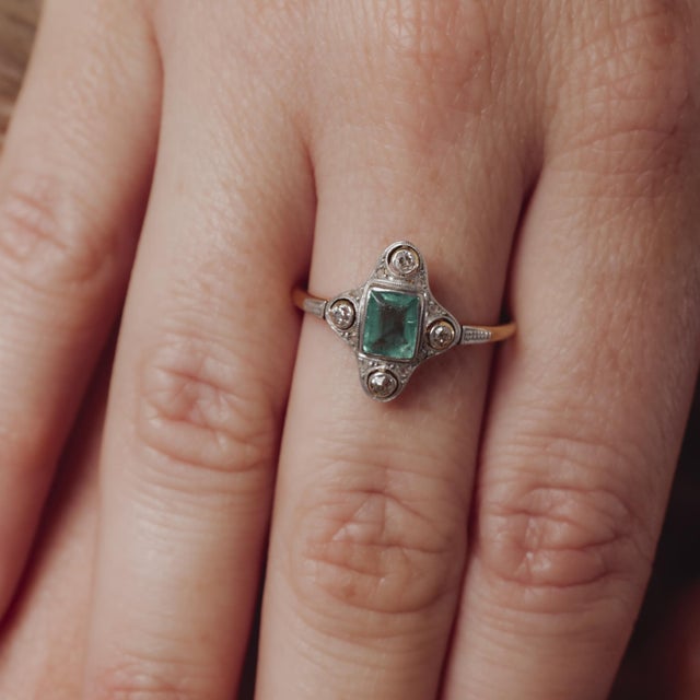 A refined Victorian 18k yellow gold and platinum ring centered with a 0.60 carat emerald, accented by delicate rose and...