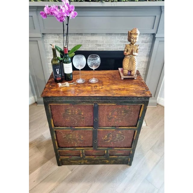 A scarce rustic Tibetan hand carved and painted cabinet, born in the 19th century, hand-crafted of solid elm and fir wood,...