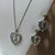 Pendant shaped in heart with a teardrop dangle. Heart shape earrings dangle from solitary rhinestone stud. Chain is marked...