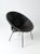 A mid-century modern black wicker saucer chair with a sleek, minimalist profile. the rounded woven seat creates bold...