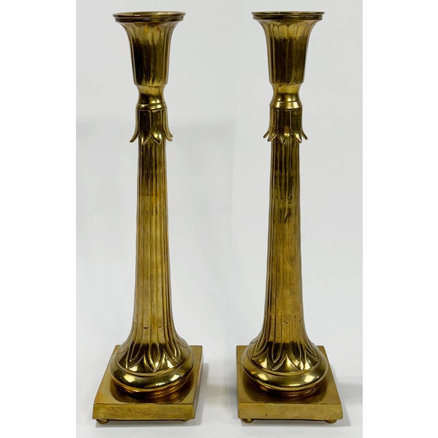 Pair of large vintage fluted brass candlesticks featuring solid square bases with almost floral embossed motif to stems....
