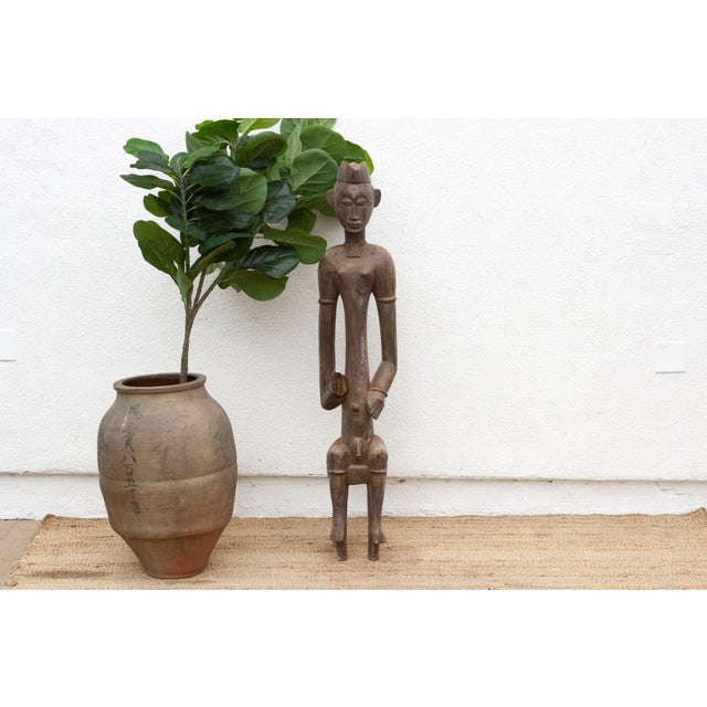 Presenting a compelling Senufo seated male figure, standing at 52 inches tall with a base measuring approximately 10" x...