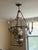 Beautiful vintage chandelier featuring an ornate cast-metal frame with intricate scrollwork and a warm antique brass...