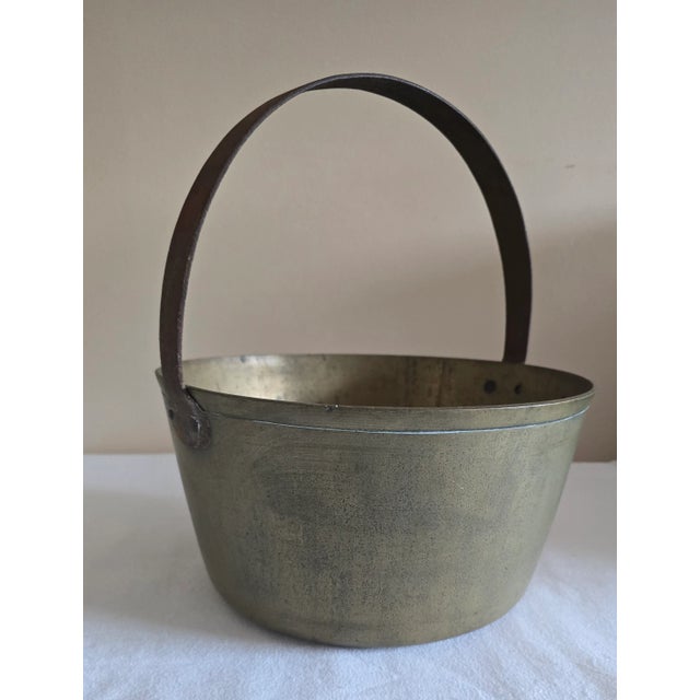 Description: Heavy brass pot Thick forged iron handle Handle attached by rivets Condition: Excellent Minor signs of age...