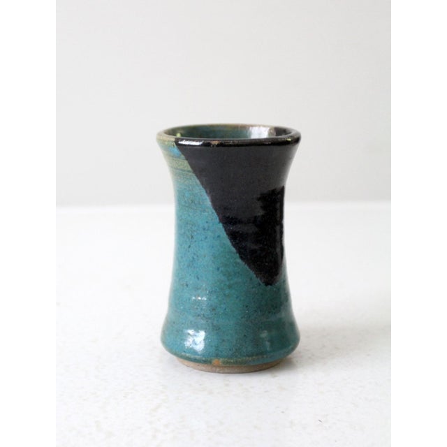 A striking studio pottery vase featuring a bold, hand-applied glaze of black, brown, and turquoise. The glossy finish and...