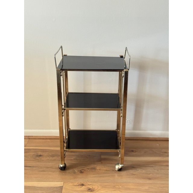 Vintage three-tier bar cart featuring a gold-tone metal frame, smoked plastic shelves.
