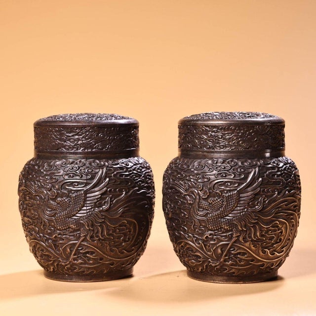 This is a matching pair of silver-plated tea caddies or covered jars, featuring elaborate high-relief (repoussé)...