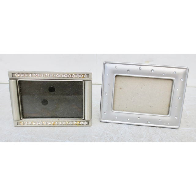 Two portrait photo frames in silver and rhinestone designs. The smaller measures 3.5" by 2.5" and the larger 2.9" by 3.9"....