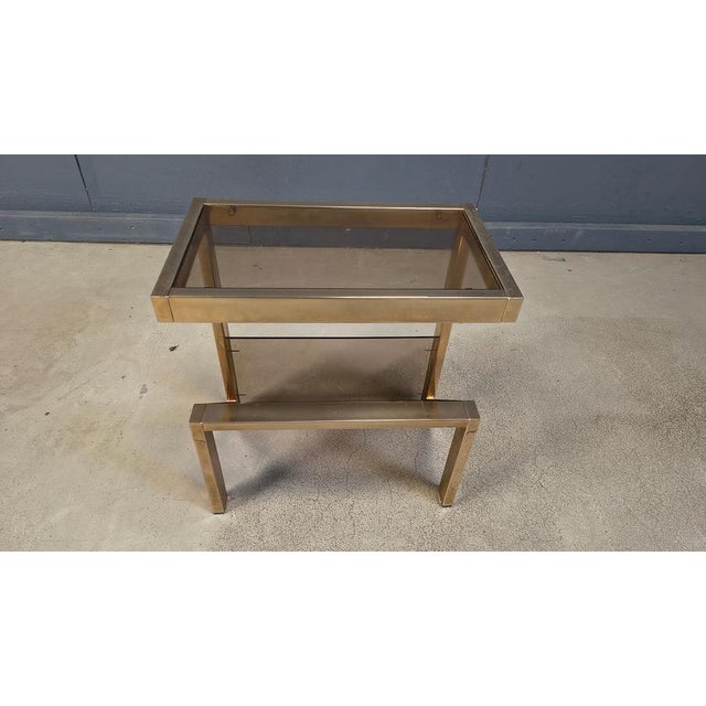 Seventies brass and smoked glass side table with magazine holder. This table has a N shaped frame. All original glass, no...