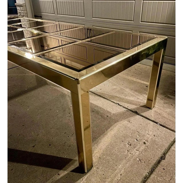 Mid-century modern brass and bronze tinted glass Parson’s style dining table, spanning over eight feet with one leaf, just...