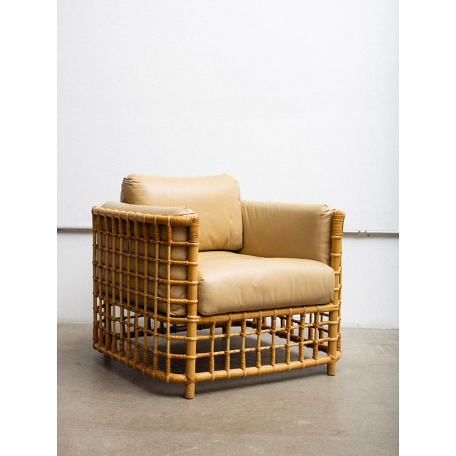 A rattan chair and ottoman attributed to Henry Olko. Grid pattern silhouette with original beige leather upholstery. Henry...
