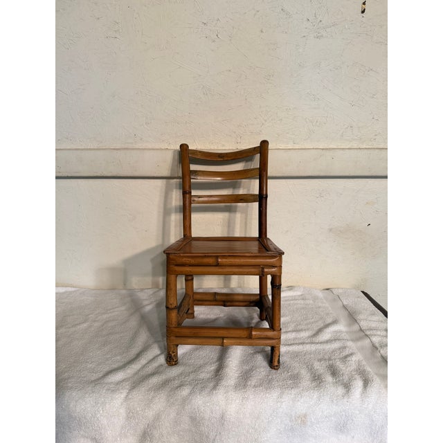 Bamboo ladder back child's chair. The chair has a three-slat ladder back and a square seat design. Visible wear and patina...