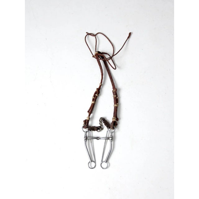 This is a vintage leather horse bridle. Brown braided leather shapes the equestrian tack with silver tone metal bit....