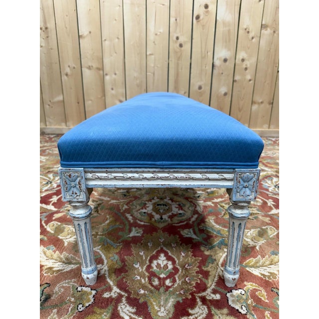 Large louis xvi style bench in carved and painted wood, displaying an antique patina with signs of wear that reveal the...