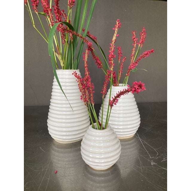 This is a set of three white hand-thrown contemporary vases with distinctive grooved texture. Pear-shaped, approximately...