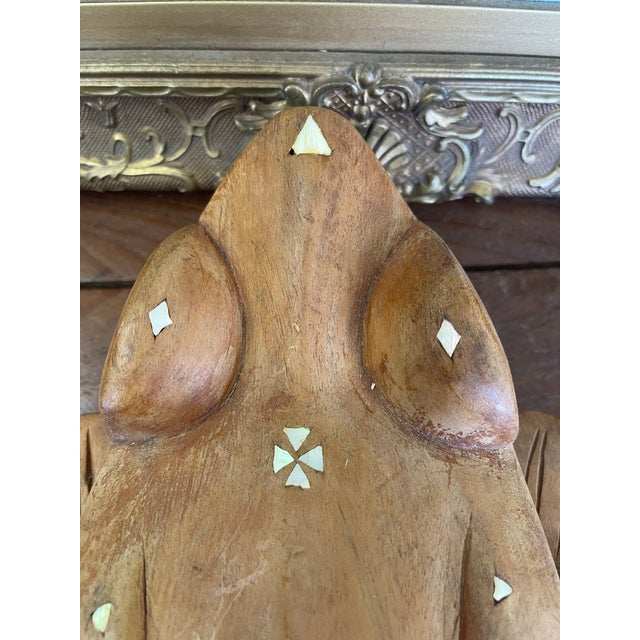 A beautifully hand-carved wooden wall plaque in the form of a stylized frog, featuring geometric inlay and painted tribal-...