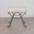 Iron stool with beautiful curved and looped base with matte black painted finish. Rectangular cushioned seat upholstered...
