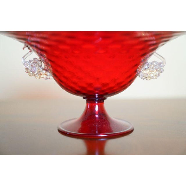 A striking vintage ruby red Murano art glass footed compote featuring a wide flared bowl, short pedestal base, and applied...