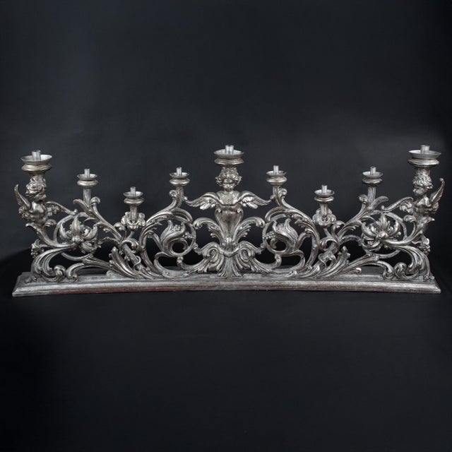 An exuberant 19th-century Italian Rococo-style silver-leaf altar candelabra, richly carved in wood with the lively...